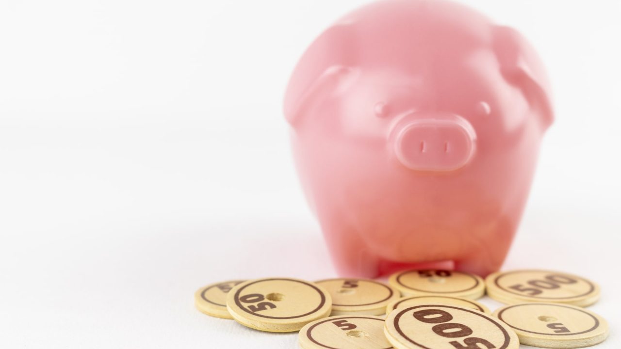 豚の貯金箱と木でできたおもちゃの硬貨
